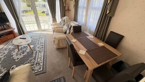 A cozy living room with a sofa, a wooden table, and a TV. - 2 Bed Lodge Sleeps 5 - Pet Friendly, Wifi, Parking (Skegness)
