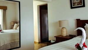 A hotel room with a bed, a nightstand, a lamp, a mirror, and a picture on the wall. - Carey Apartment in Carey Residential, White Sands, 5 Minutes from the Beach. (Punta Cana)