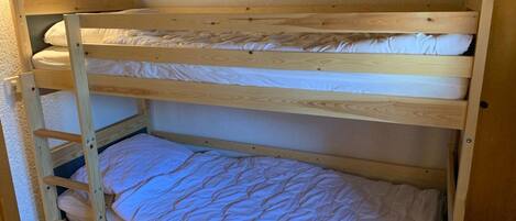 A bunk bed with three levels, each with a mattress and pillows.