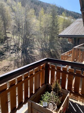 Un balcone in legno con vista su un pendio boscoso.