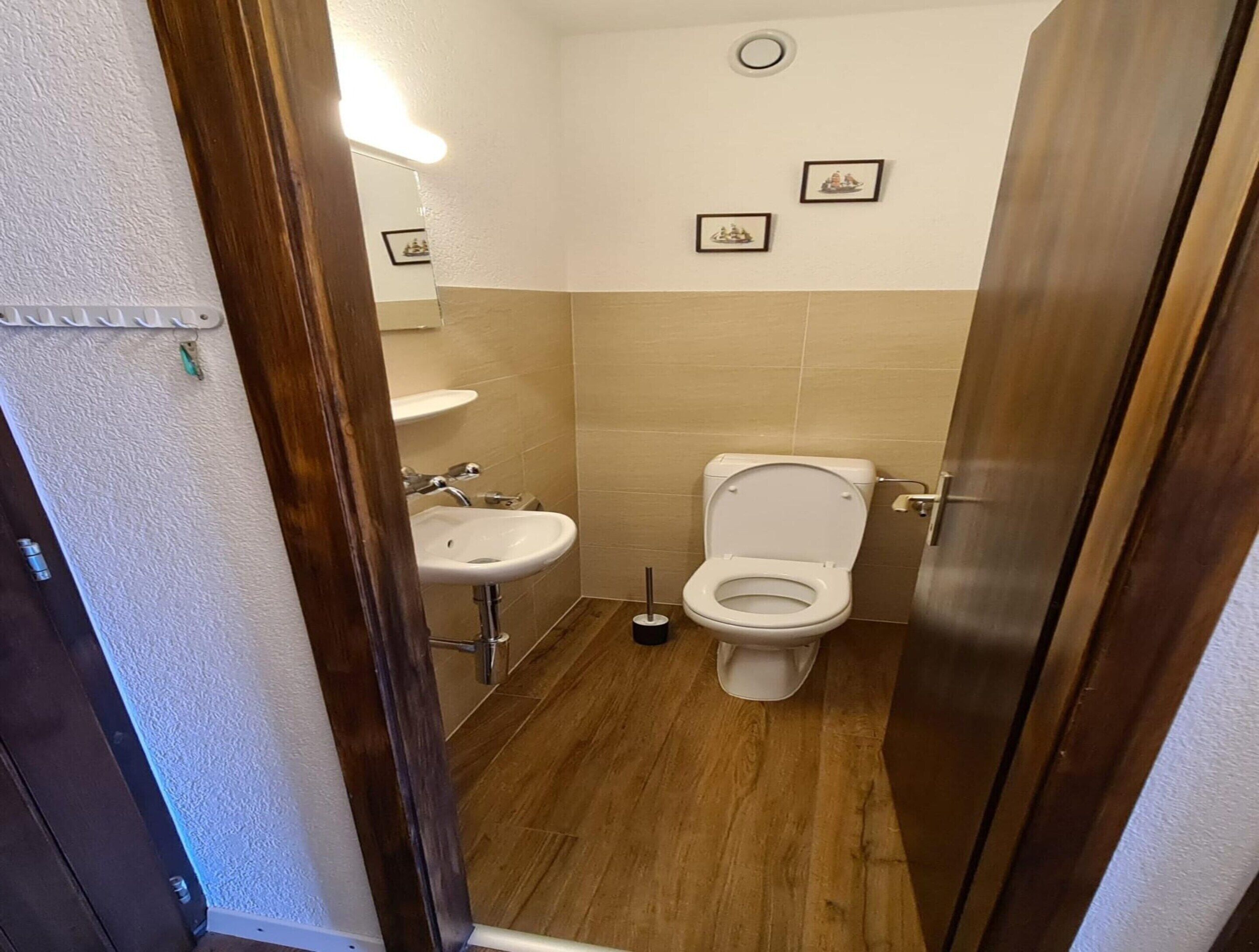 Et lille badeværelse med toilet, vask og spejl.