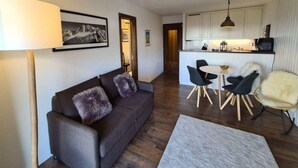 Un salon moderne comprenant un canapé, une table à manger avec des chaises, un coin cuisine avec des placards et une lampe.