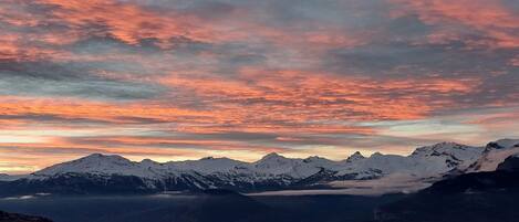 A mountainous landscape with snow-covered peaks and a valley below.