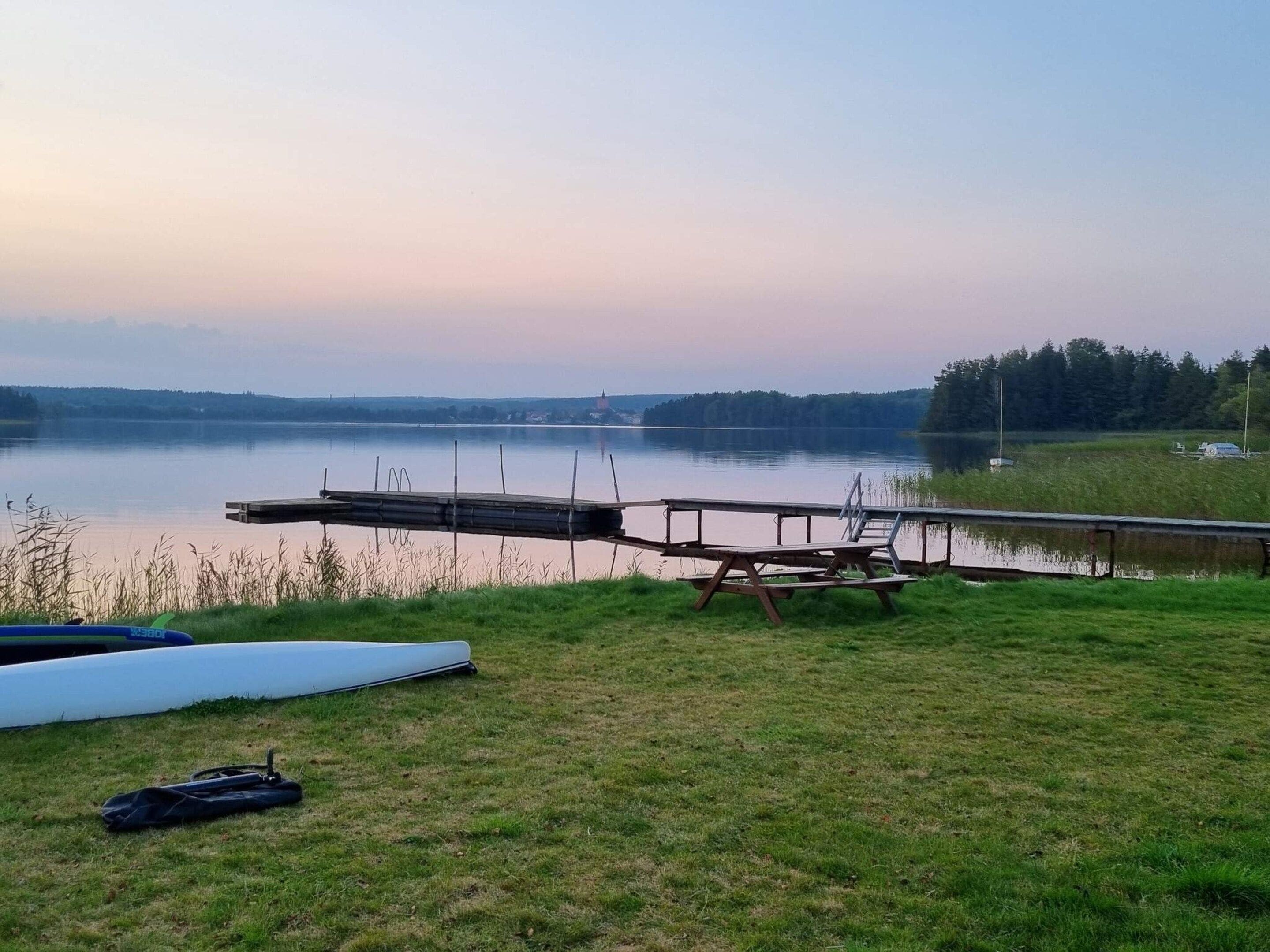 A lakeside view with a dock, picnic table, and boats.