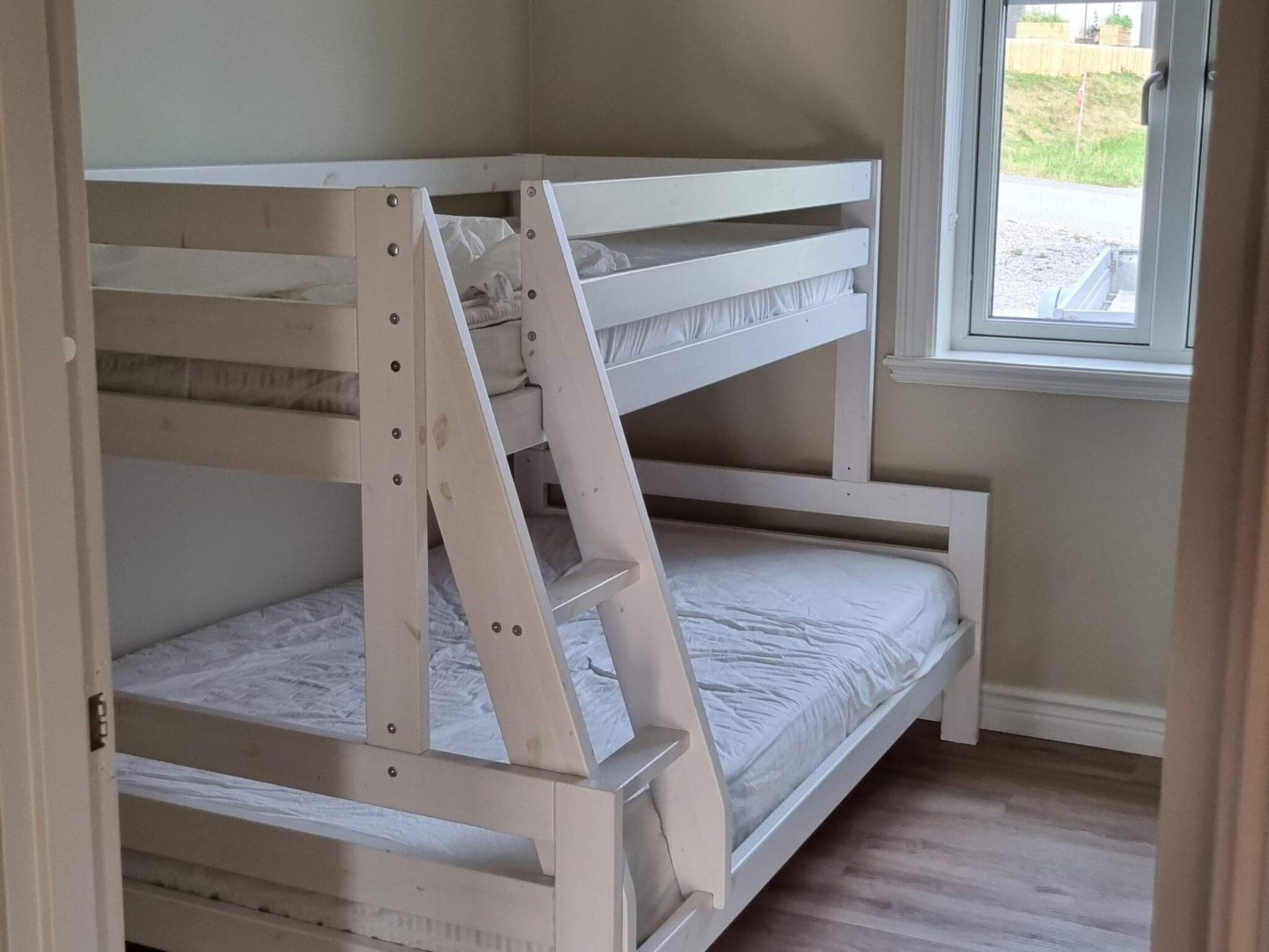 Una cama litera con estructura de madera y ropa de cama blanca.