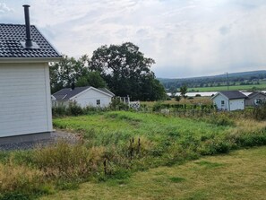 A rural setting with a white building, a fenced area, and a large tree.