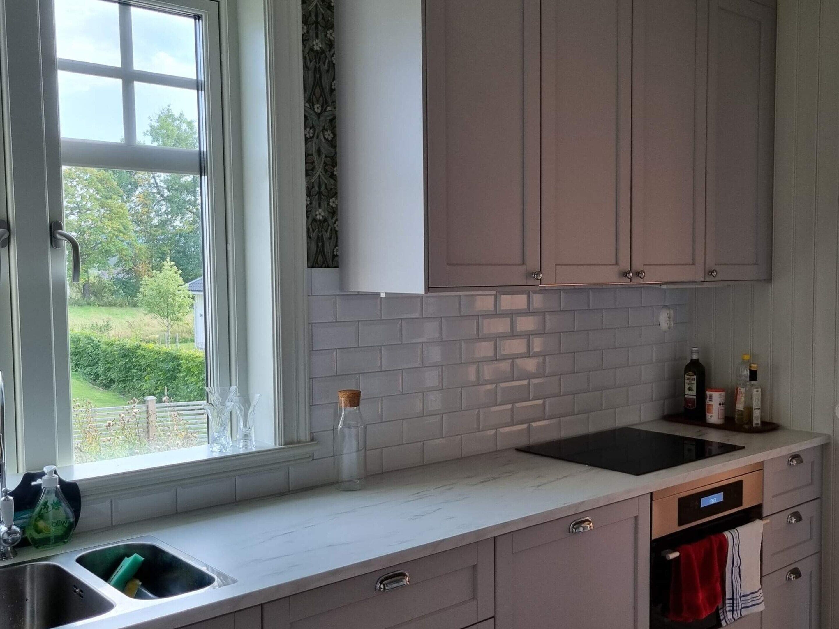 Una cocina con ventana, un lavamanos, una estufa y armarios.