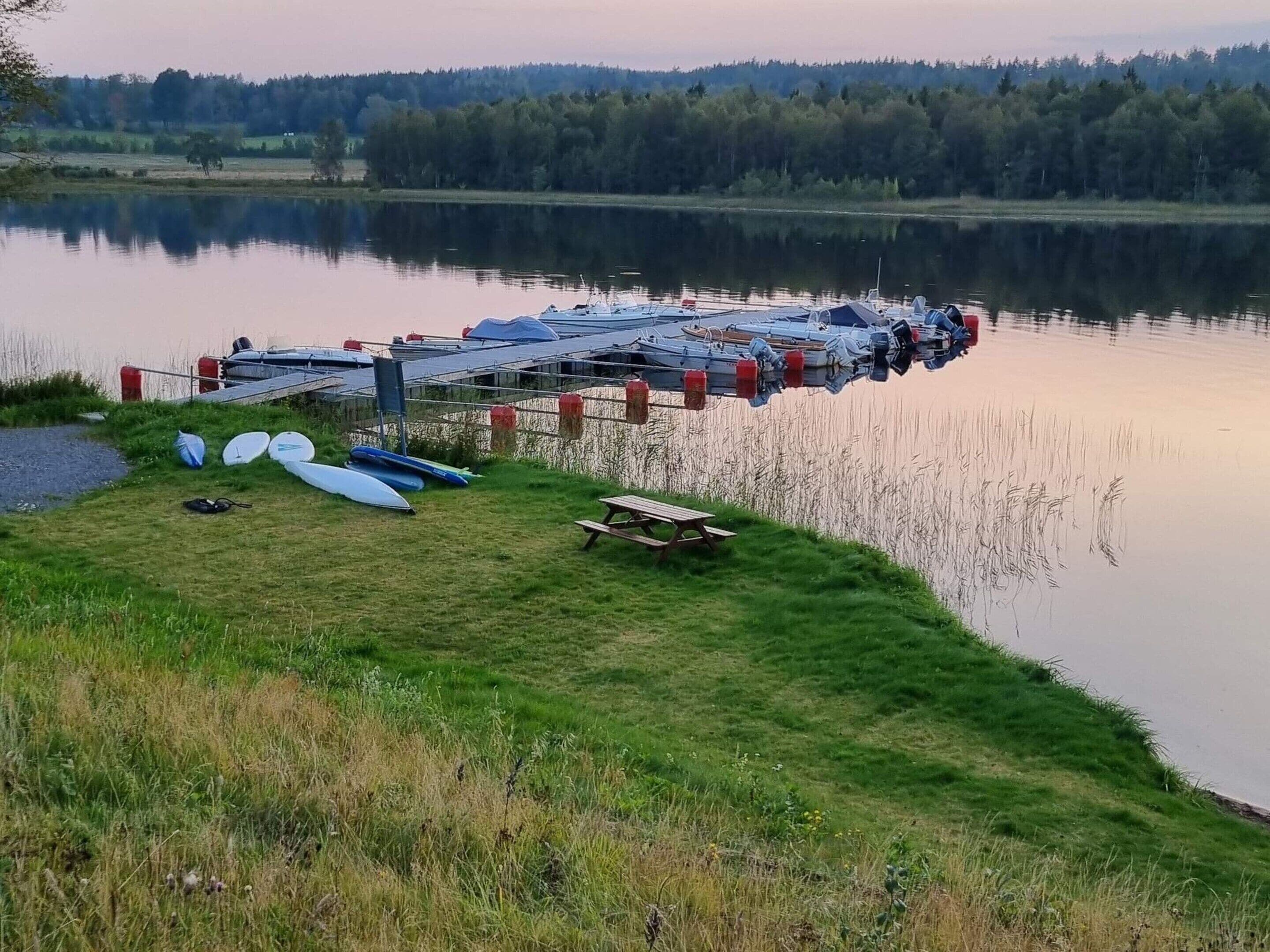 Un molo con barche e un tavolo da picnic in riva a un lago tranquillo.