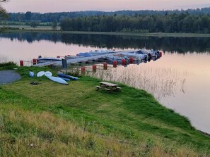 Laituri, jossa on veneitä, ja piknikpöytä rauhallisen järven rannalla.