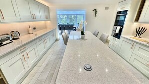 Una cocina moderna con armarios blancos, una isla grande y una zona de comedor con sillas y una mesa.