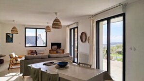 Uma sala de estar ampla com uma mesa de jantar, cadeiras, sofá e televisão.