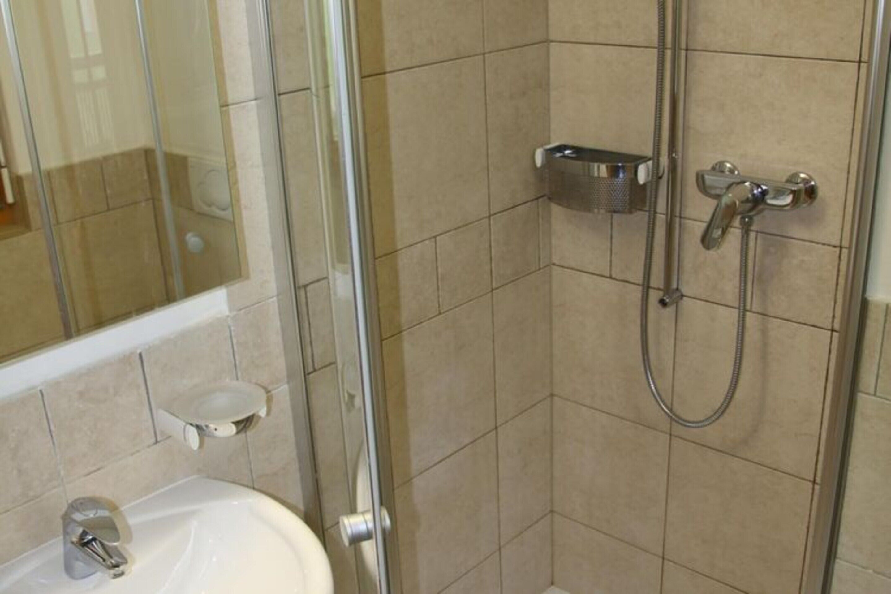 A bathroom with a glass shower enclosure, a sink, and a toilet.