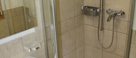 A bathroom with a glass shower enclosure, a sink, and a toilet.