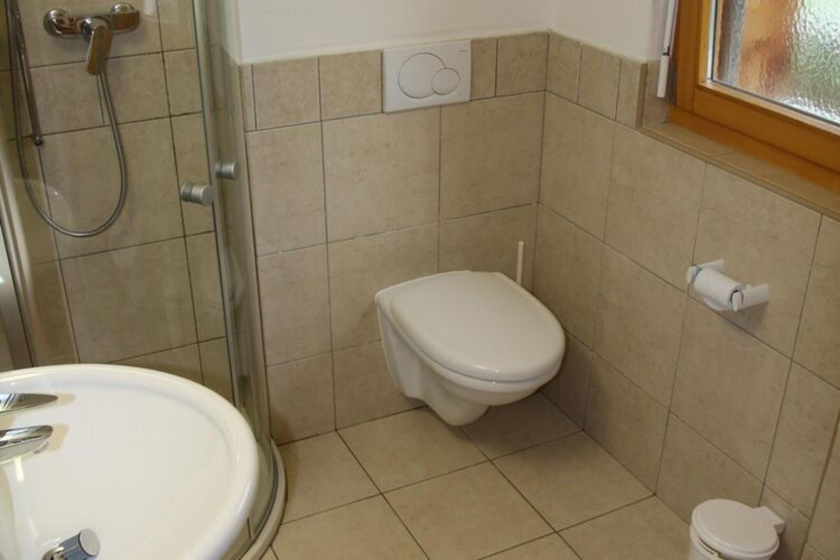 A small bathroom with a toilet, a shower, and a sink.