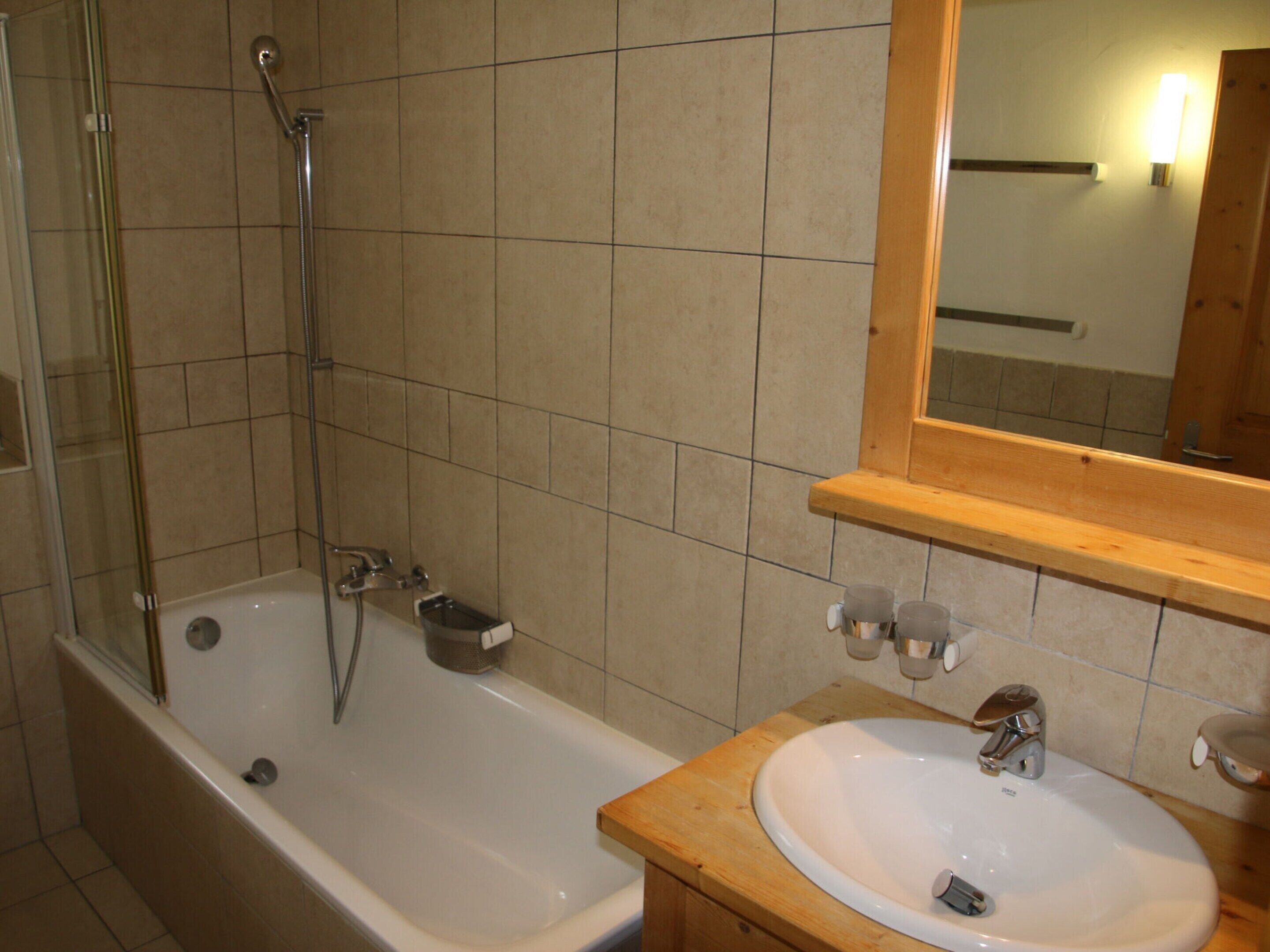 A bathroom with a bathtub, a sink, and a mirror.
