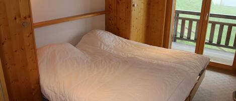Una cama individual con cabecera de madera y vista a un balcón.