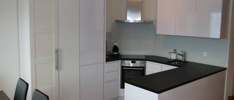 A modern kitchen with white cabinets, a black countertop, and a built-in oven.