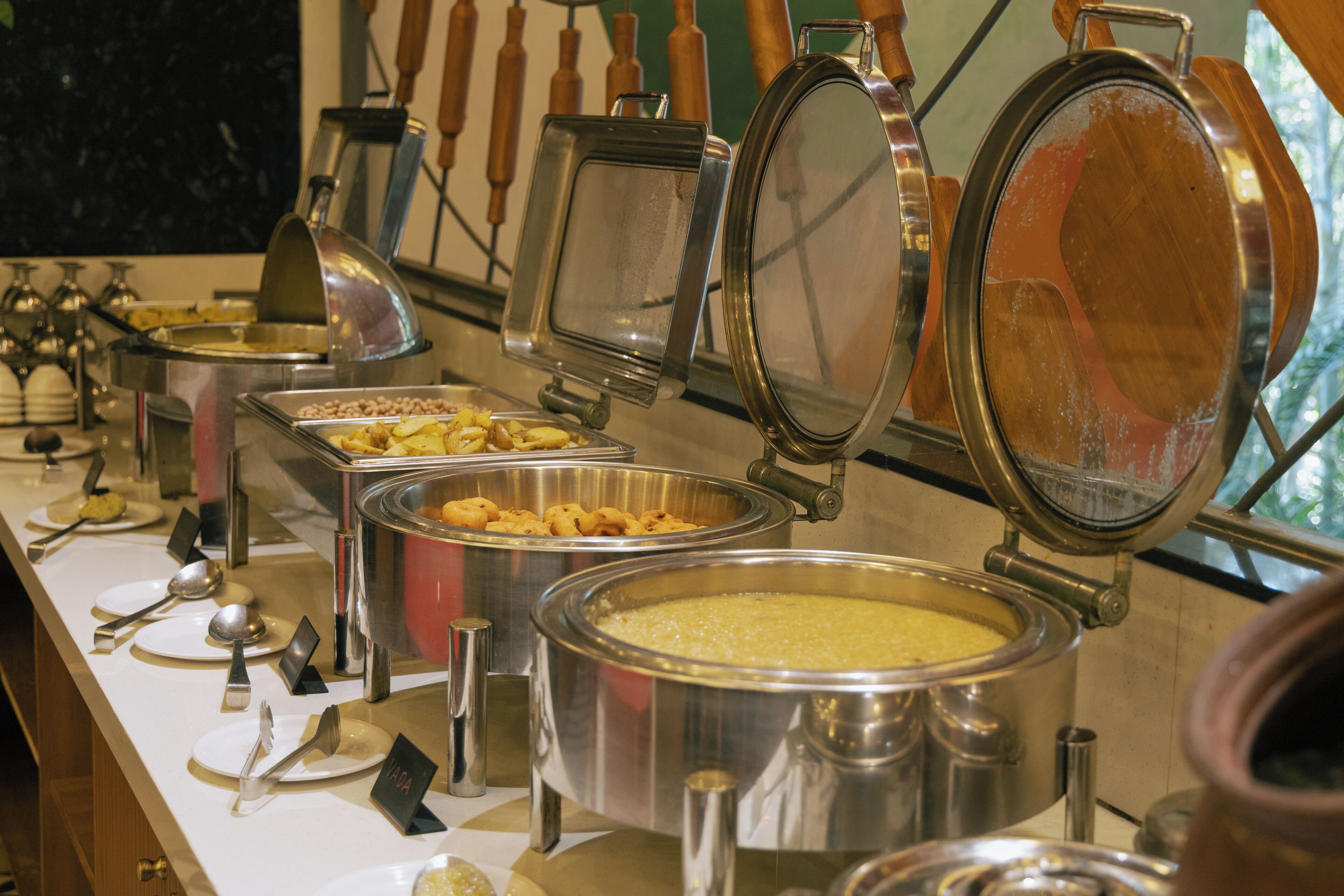 Un buffet avec plusieurs points de service, chacun équipé d’un récipient en métal et d’une cuillère.