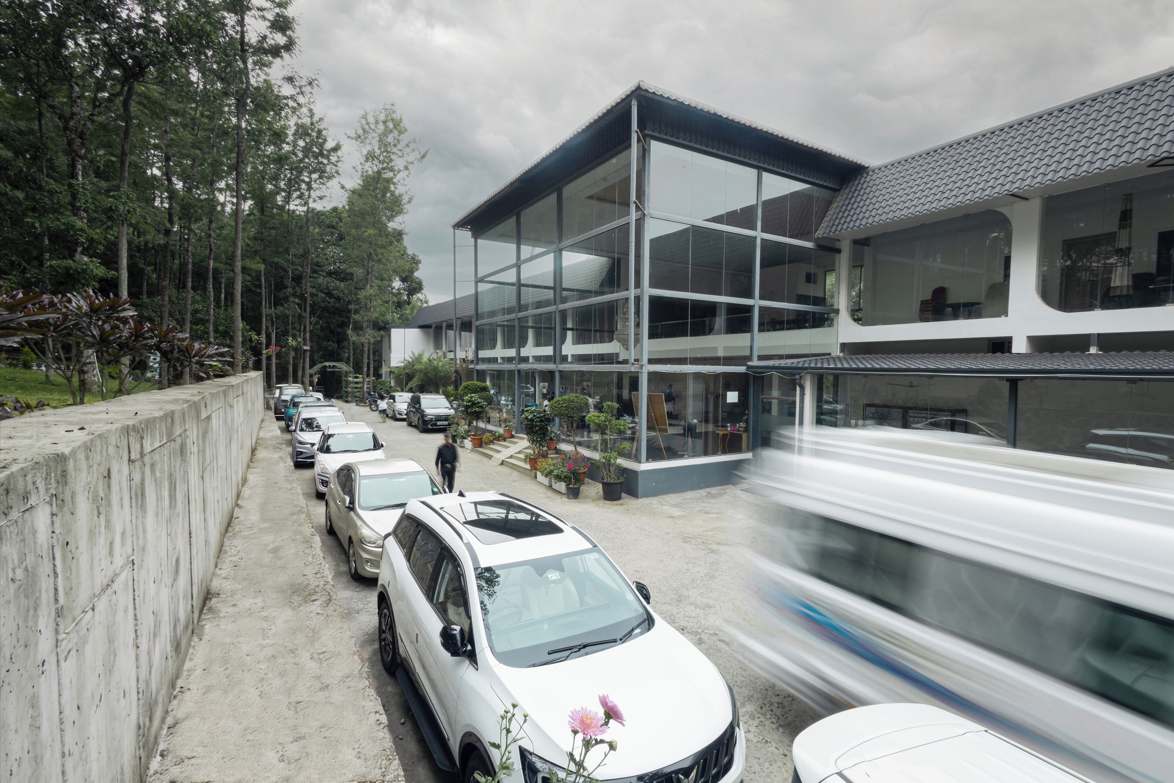Ein modernes Gebäude mit großen Fenstern, einem Parkplatz mit Autos und einem Zug im Hintergrund.