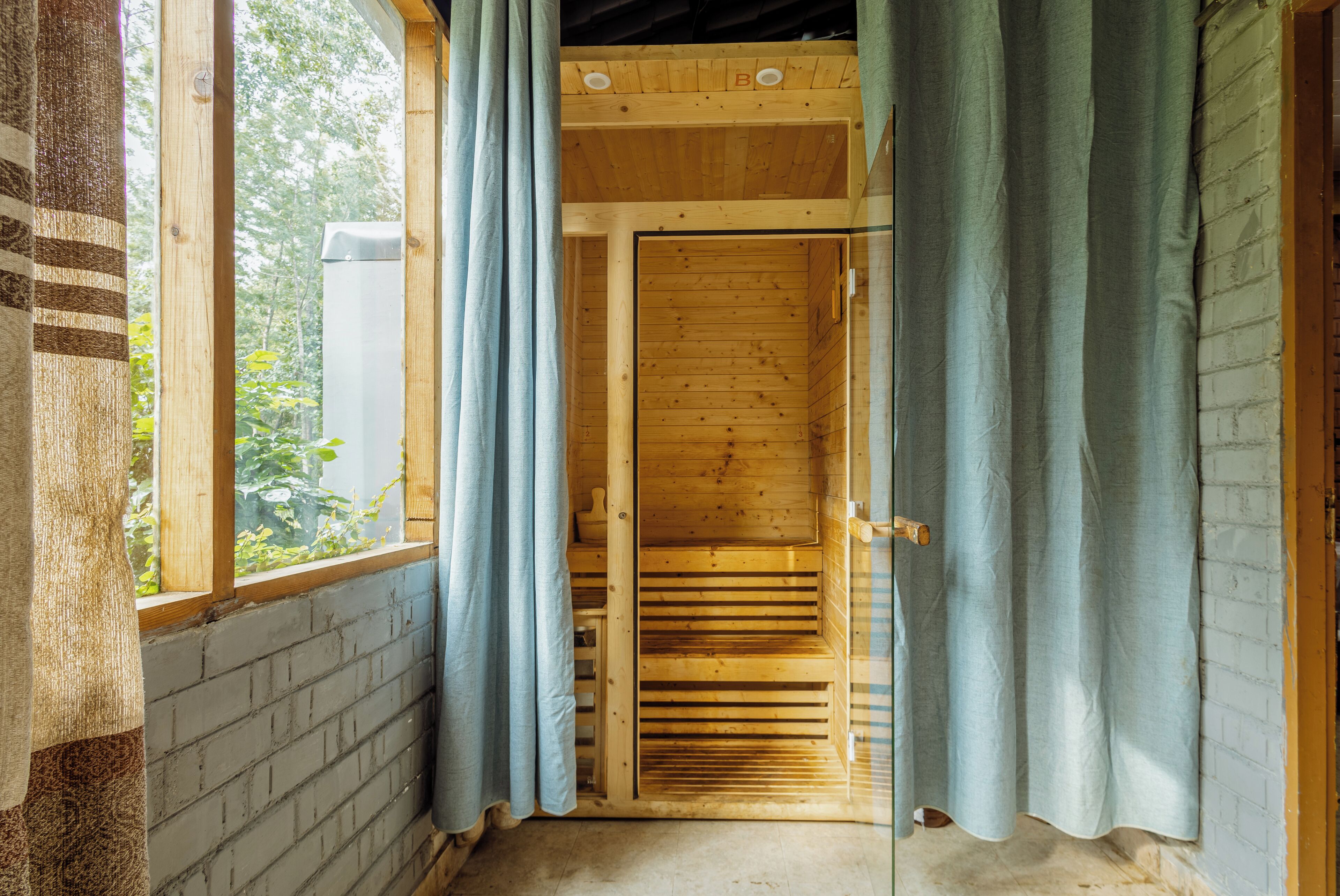A wooden interior with a window, curtains, and a door.