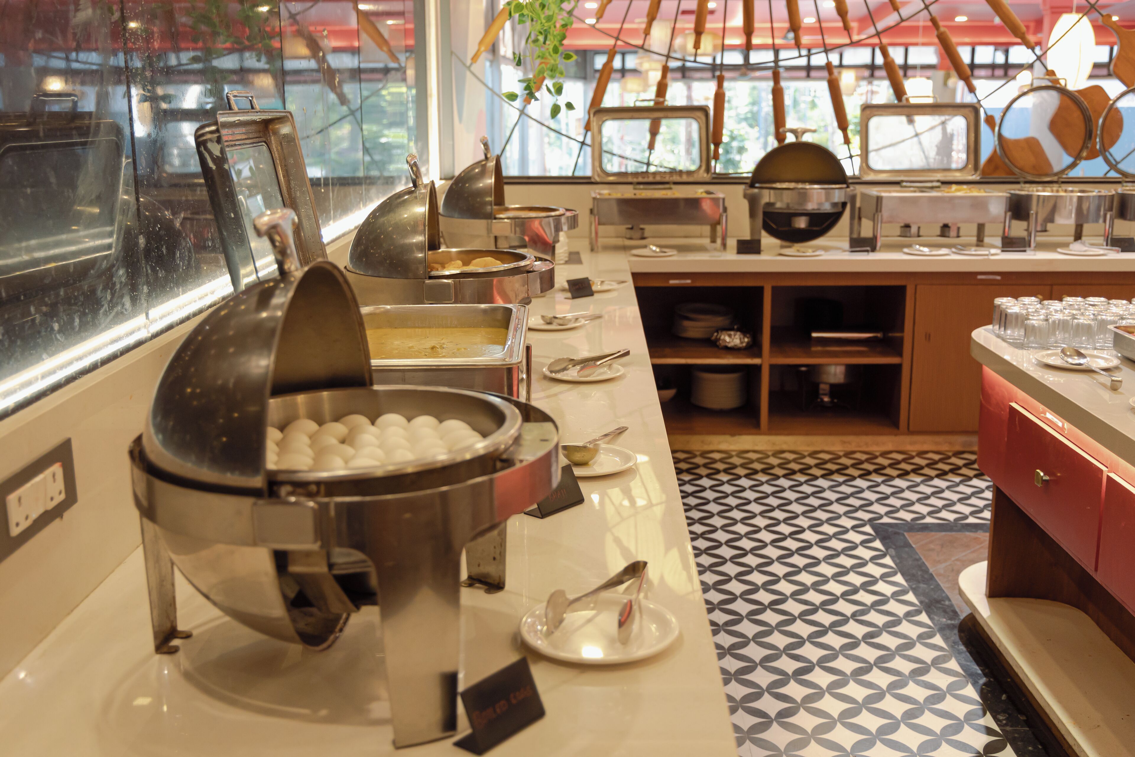 A buffet setup with various food containers and utensils.