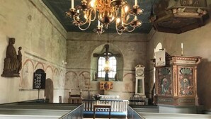 Ein Innenraum mit Kirchenbänken, einem Chandelier, einer Statue und einer Uhr.