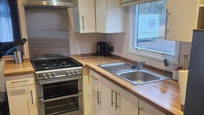 A compact kitchen with a gas stove, oven, and a window with a view of an RV. - Dunooncaravan/2bed/sleeps4/scenicwwalks/tv/wifi (Dunoon)