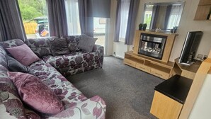 A cozy living room with a sectional sofa, a fireplace, and a TV. - Dunooncaravan/2bed/sleeps4/scenicwwalks/tv/wifi (Dunoon)