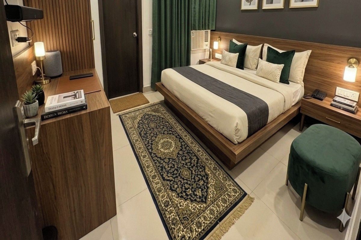Una habitación de hotel moderna con una cama grande, un escritorio, una silla, una lámpara de pie, una lámpara de suelo, una cortina verde y un ventilador de techo.