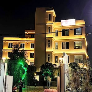 Hotel de vários andares com varandas iluminadas e uma placa indicando um restaurante.