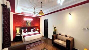 A hotel room with a bed, a sofa, a coffee table, and a dining table with food.