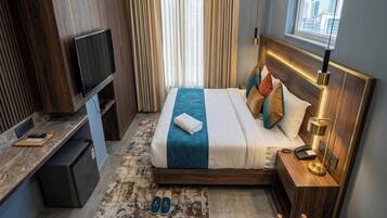 A hotel room with a bed, bedside table, TV, and a view of the city.