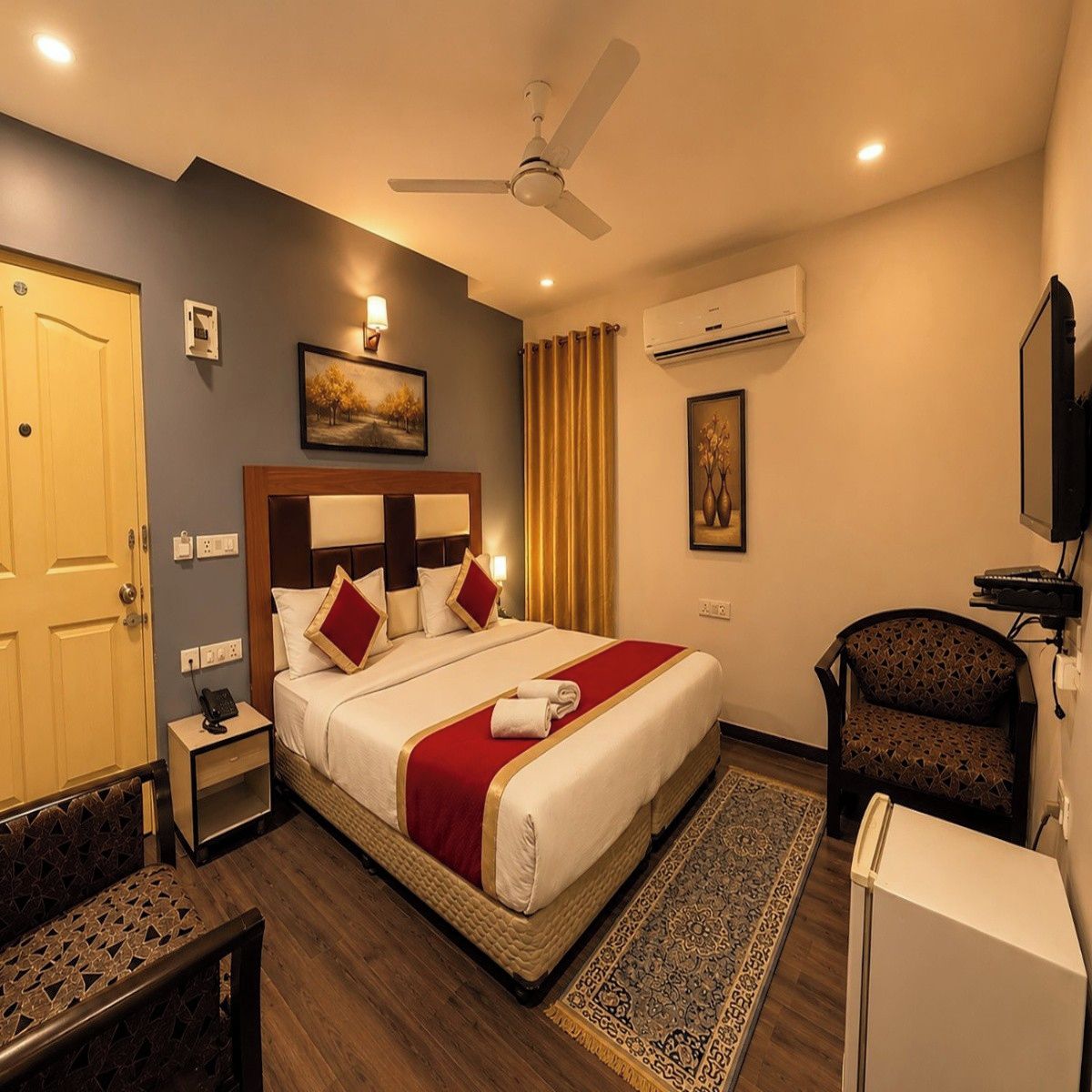 A hotel room with a bed, bedside table, chair, and a television.