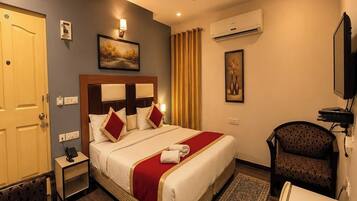 A hotel room with a bed, bedside table, chair, and a television.