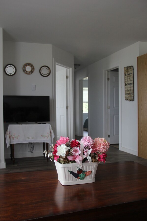 A dining area with a wooden table, a white tablecloth, and a floral centerpiece. - Cottage with three bedrooms in the Center of Cavendish (New Glasgow)