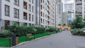 Un edificio moderno con varios pisos, amplias ventanas y un césped verde cuidado con bancos.