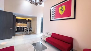 A modern living room with a red sofa, a glass coffee table, and a dining area with a kitchen in the background. - Apartamento Morelos SLP Centro Historico (San Luis Potosi)