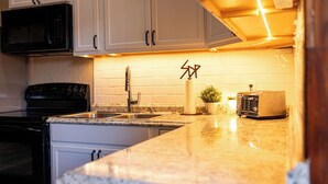 Una cucina con mobili bianchi, un forno a microonde nero, un tostapane e un lavandino.