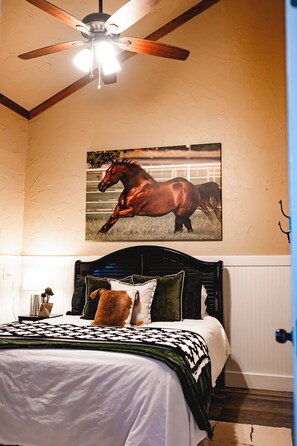 A bedroom with a bed, a ceiling fan, a mounted horse painting, and a door. -
Escape to a cozy, four bedroom two-bath retreat on a beautiful working ranch! (Fort Worth)