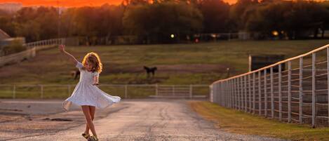 A rural road with a fence on one side and a sunset in the background.