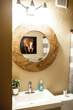 A bathroom with a round mirror, sink, and a potted plant. -
Escape to a cozy, four bedroom two-bath retreat on a beautiful working ranch! (Fort Worth)