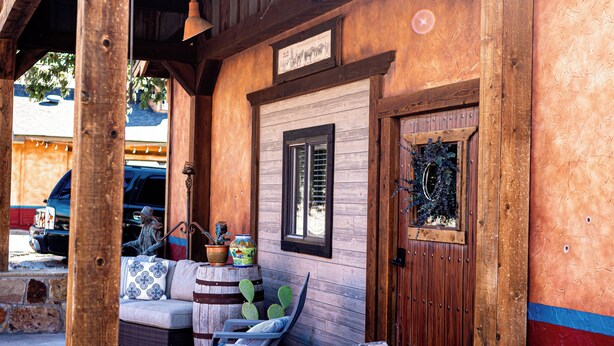Un portico in legno con un muro in pietra, una porta di legno e una panchina.