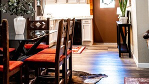 Una cucina rustica con travi in legno, una decorazione a testa di toro e un'area pranzo con sedie rosse e un tavolo in vetro.