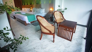 A hotel room with two beds, a dining table, two wicker chairs, and a glass partition. - Aaradhya Madu River  (Ambalangoda)