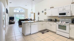 A spacious kitchen with white cabinets, a large island, and a built-in oven. - Golfview 4 bedroom villa with pool in Southern Dunes, 20 miles from Disneyworld (Haines City)