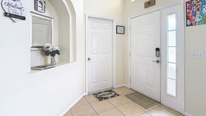 A hallway with white doors, a welcome sign, a framed picture, and a Mickey Mouse poster. - Golfview 4 bedroom villa with pool in Southern Dunes, 20 miles from Disneyworld (Haines City)