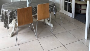 Een eetgedeelte met een ronde tafel, stoelen en een hanglamp.