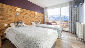 A hotel room with two beds, a wooden wall, a TV, and a view of mountains. - Hôtel Le Christiania Saint Lary Soulan (Saint-Lary-Soulan)