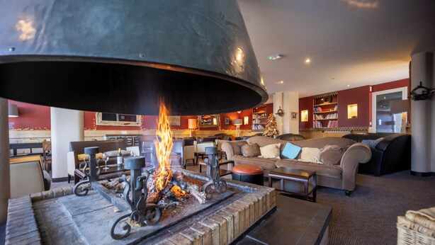 A cozy living room with a fireplace, a sofa, and a coffee table. - Hôtel Le Christiania Saint Lary Soulan (Saint-Lary-Soulan)