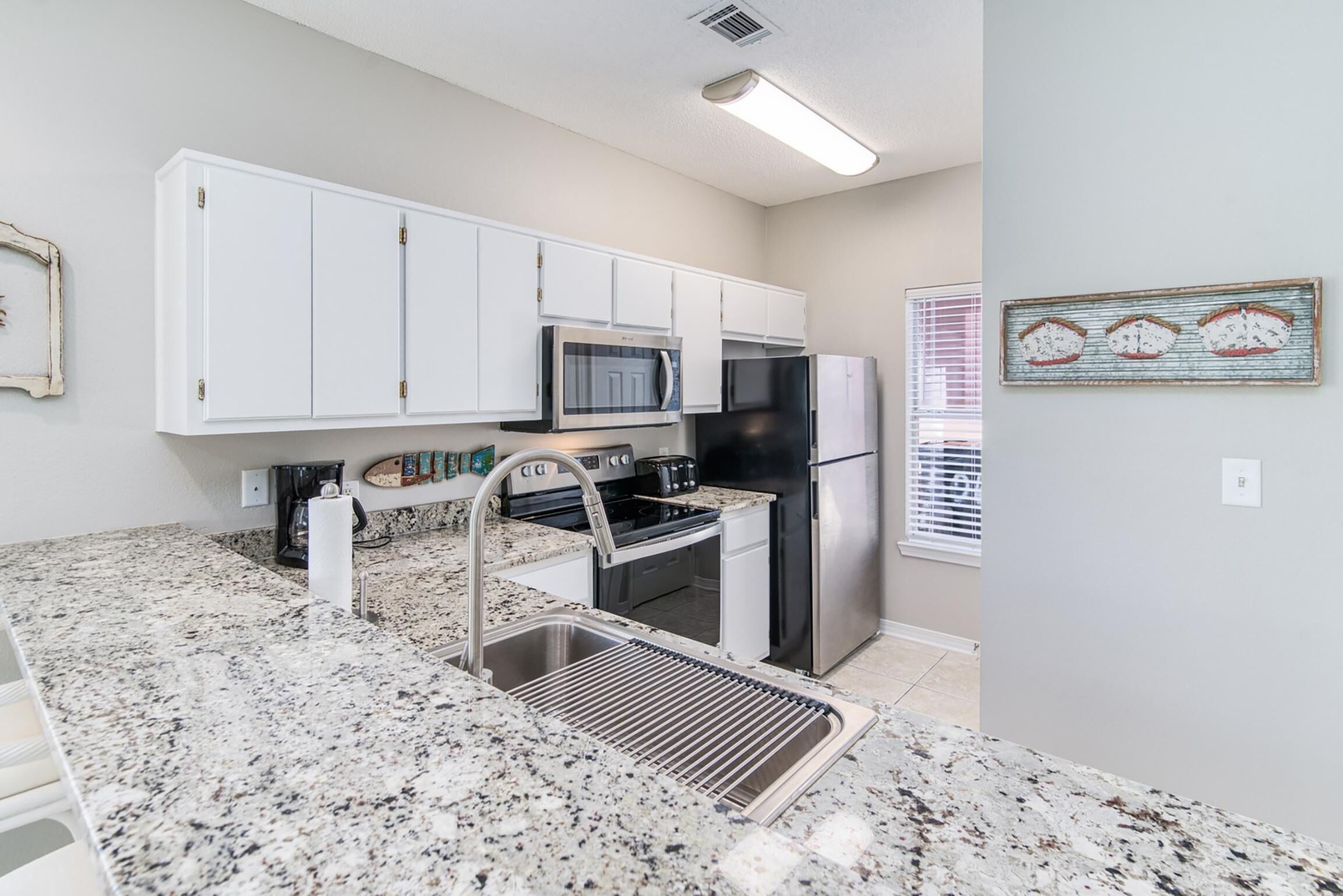 A modern kitchen with white cabinets, stainless steel appliances, and granite countertops.